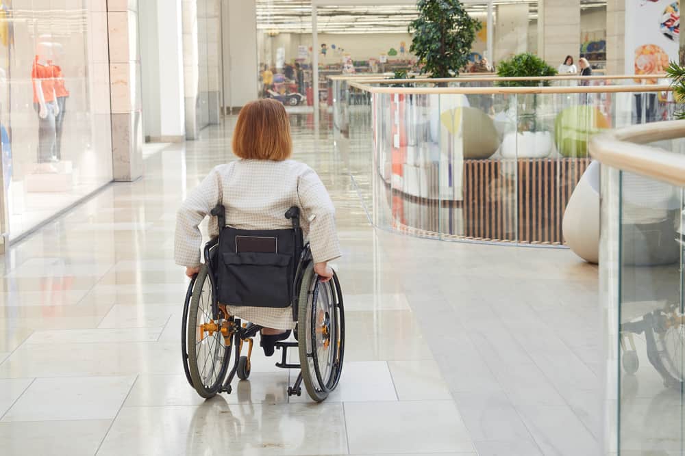 A young woman in a wheelchair navigates the second floor of a shopping mall.