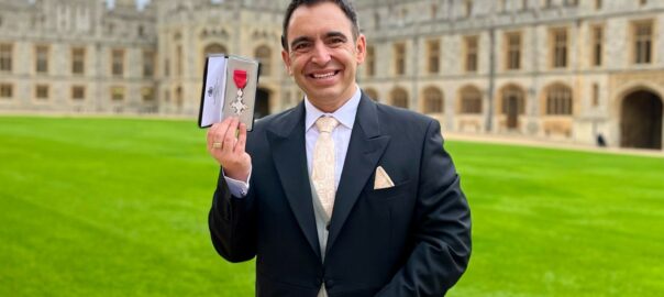 Steven Mifsud holding his MBE on the grounds of Windsor Castle.