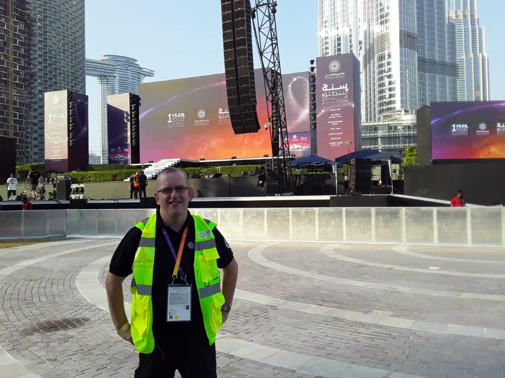 Steve Dering at Expo Dubai wearing a hi-vis. In the background a giant sign.