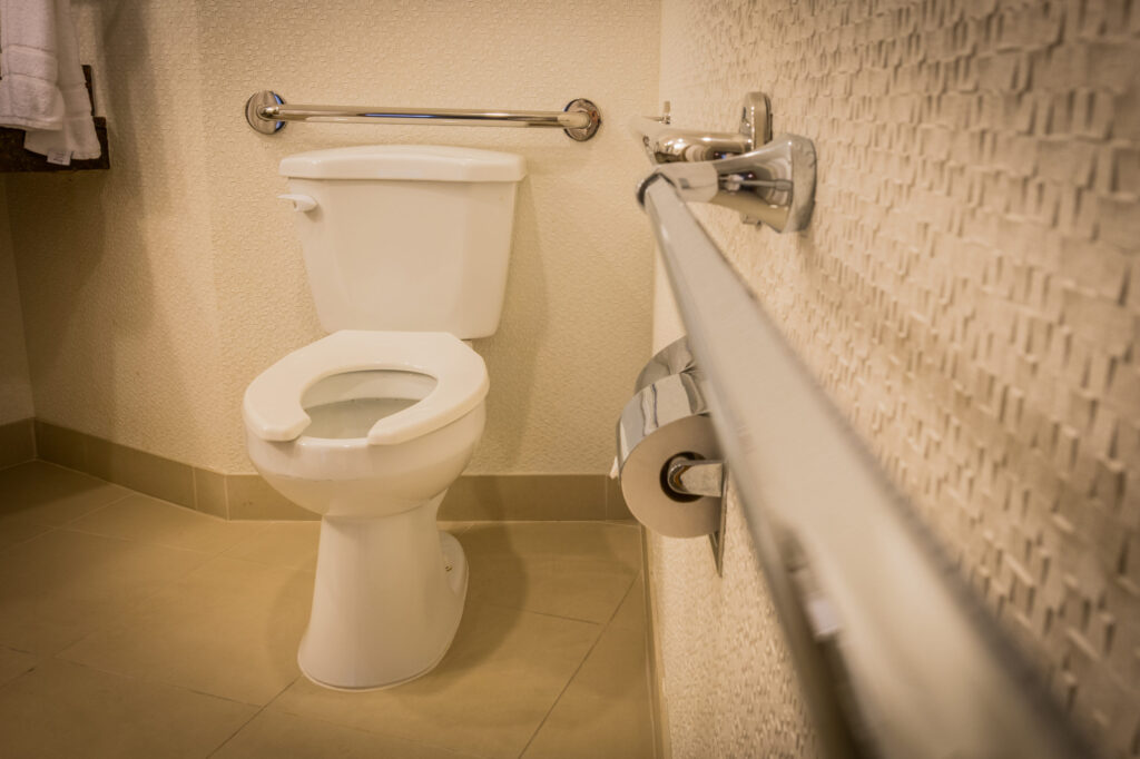 A disabled toilet bathroom with grab bars with a white interior design style.
