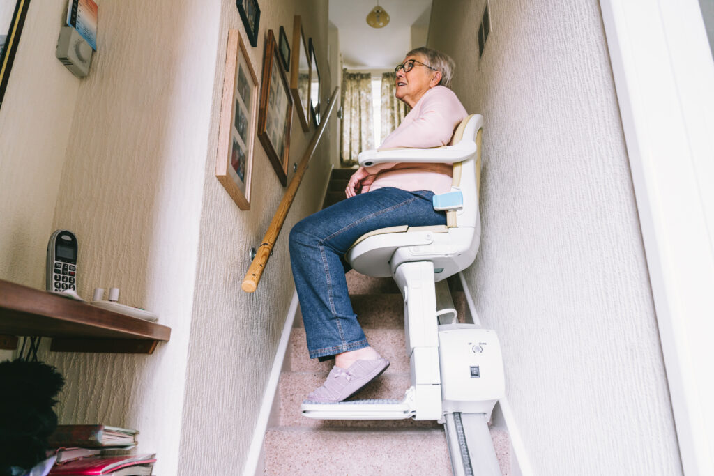 Senior woman using automatic stair lift on a staircase at her home.