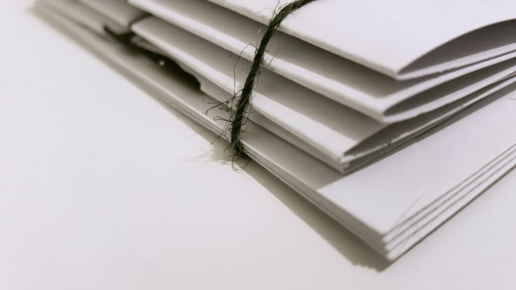 A close-up of the corner of a stack of documents. A black thick piece of string binds them together.