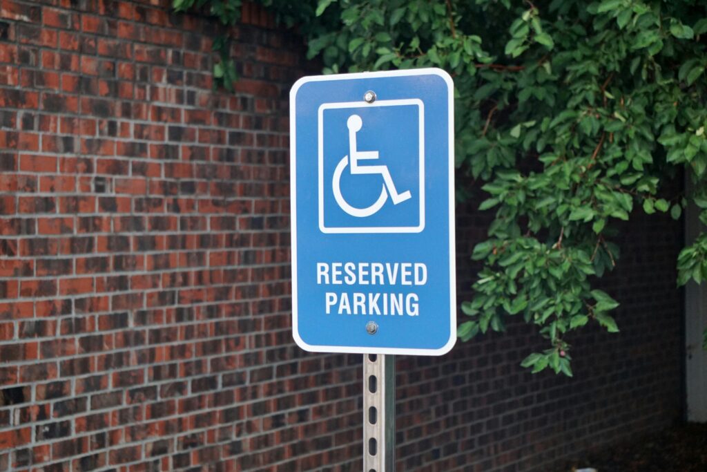 A blue accessible car parking sign with the international symbol of access displayed on it (a symbol of a wheelchair). White text reads "reserved parking".