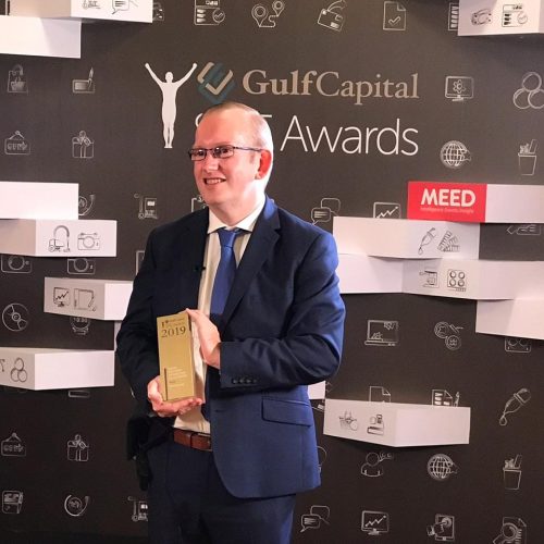 Steve Dering at the Gulf Capital Awards carrying an awards statue and smiling.