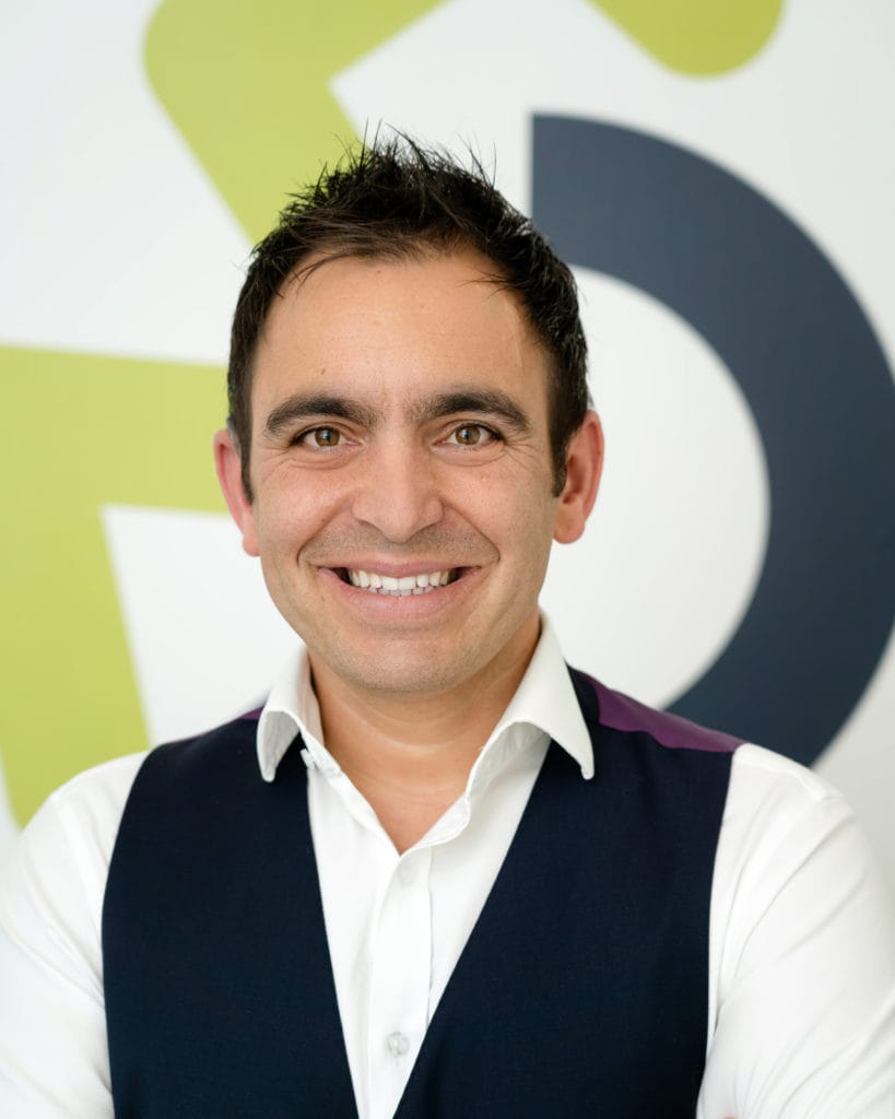 A portrait photograph of Steven Mifsud MBE smiling with the Direct Access wheelchair logo in the background.
