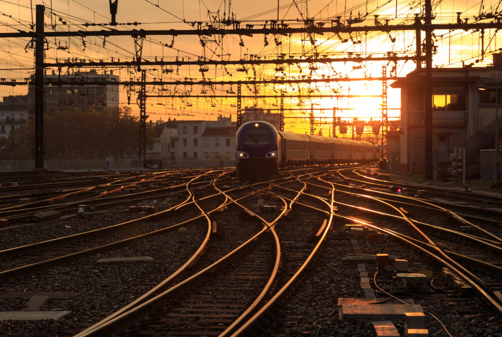 A train on the railroad tracks during sunrise.