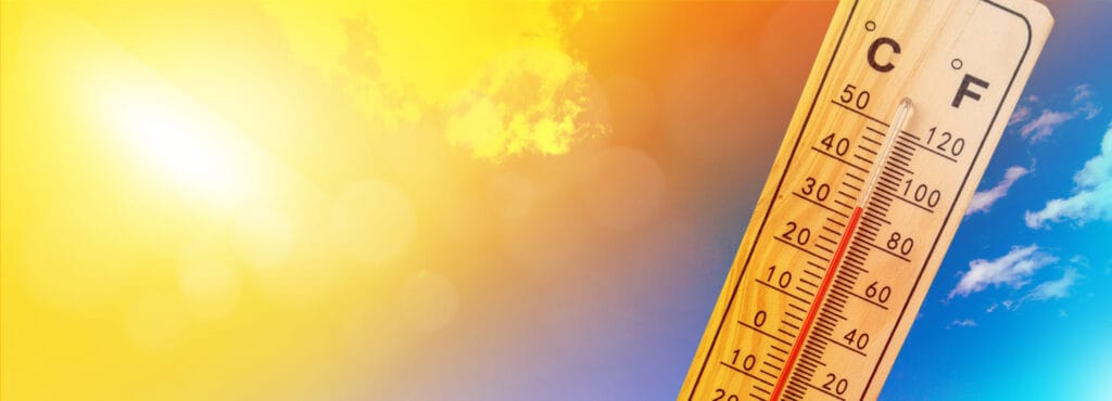 The sun brightly emanates heat from the sky, a thermometer shows the temperature is hot