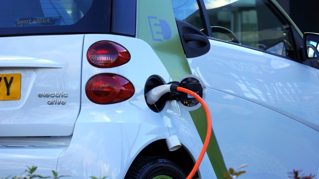 A photo of an open electric car fuel cap with a cord plugged in for charging.