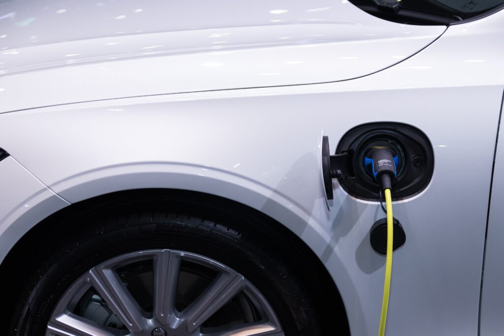 A photo of an open electric car fuel cap with a cord plugged in for charging.