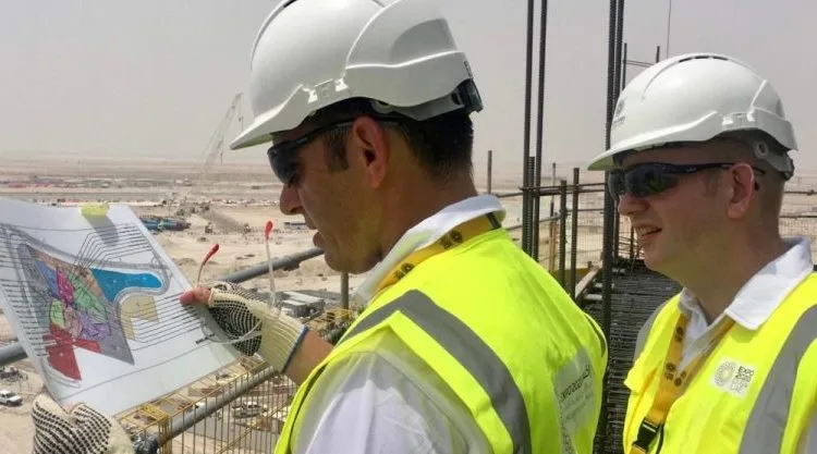 Two men (Steven Mifsud and Steve Dering) look at blueprint on a building site in the desert at Expo 2020 Dubai.
