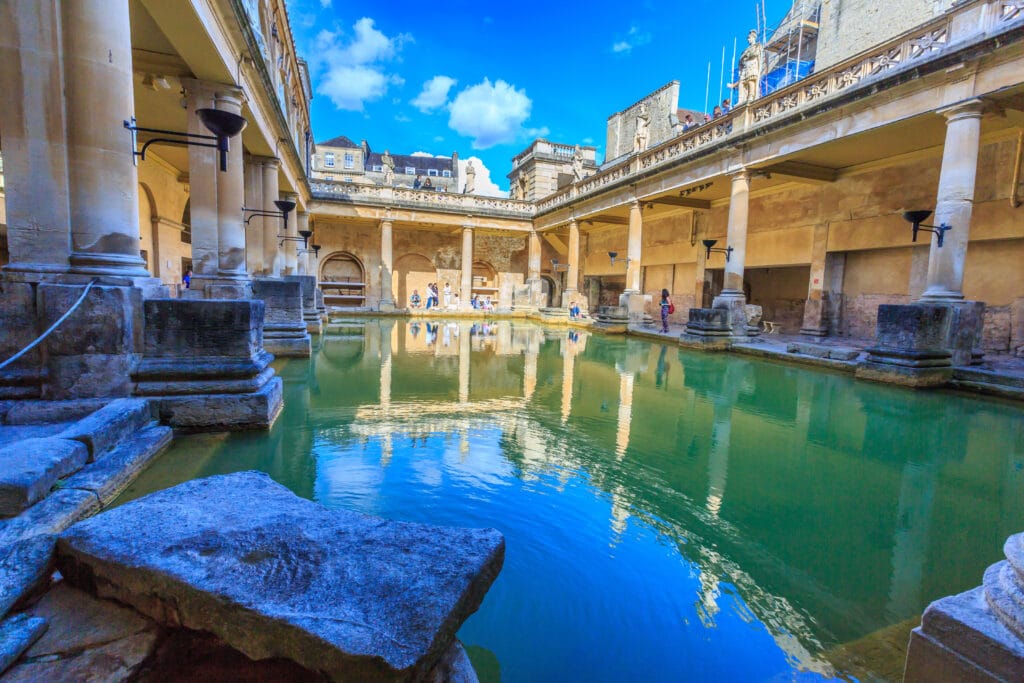 A photo of the interior of the Roman Bathhouse in the City of Bath, England as visitors explore.