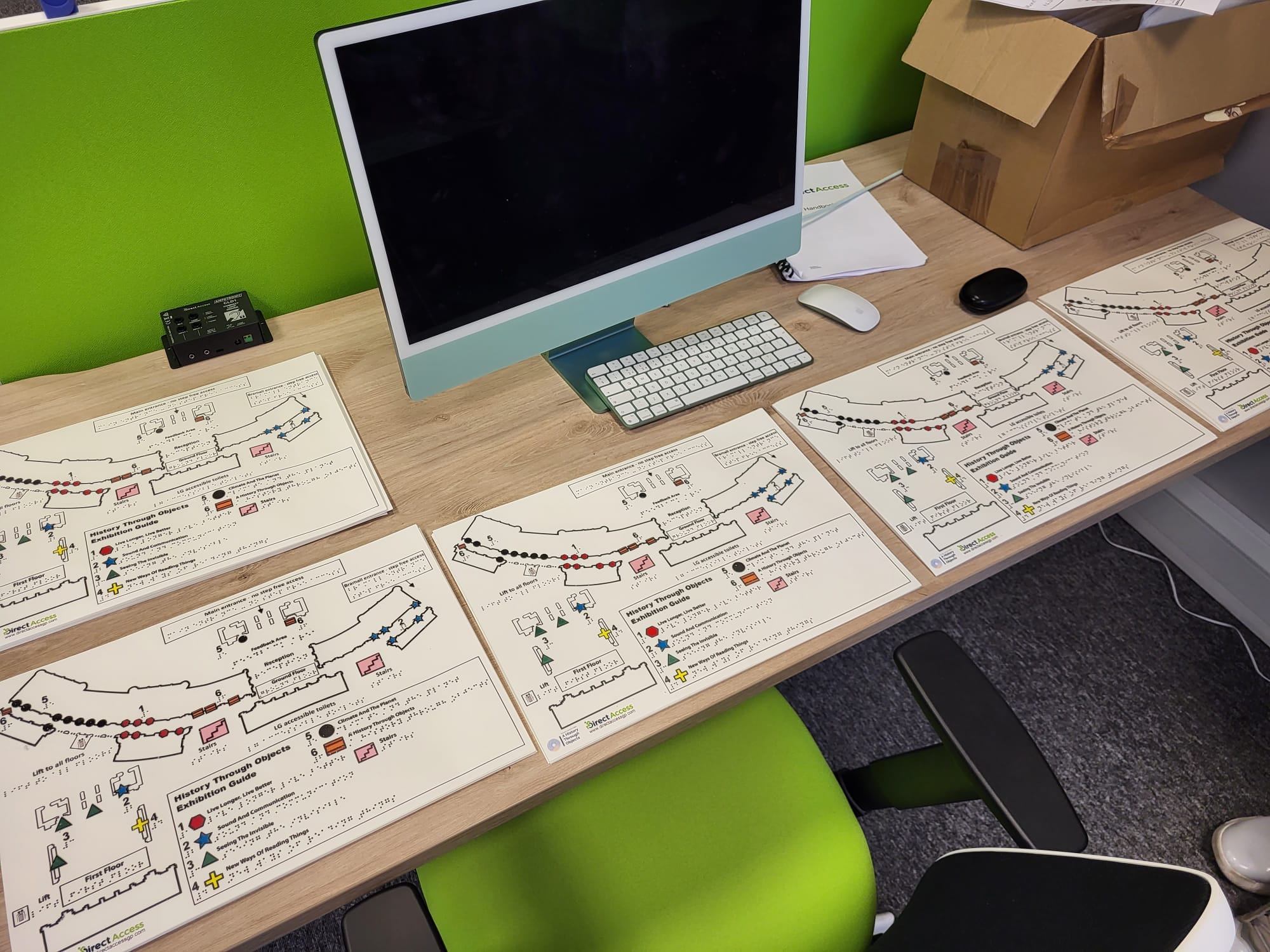 A row of five swell maps, all detailing the same location - A History Through Objects museum exhibition, spread out on a table at the Direct Access offices.