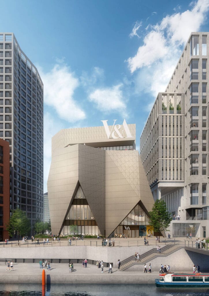 A proof of concept photo of the V and A East museum, showing a large, baige building that looks like an upside down crown. A large V and A sits on the top. Outside crowds of people commute on the open plan path space. At the forefront, a set of stairs lead down to a nearby canal with a red, white, and blue coloured boat passing by.