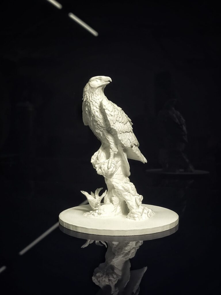 A crisp white, 3D, tactile bust of a bald eagle on a black table.