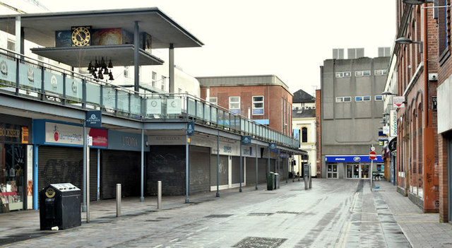 A general view of College Street in Belfast during the day; an empty street with a row of shops with their front shutters closed.
