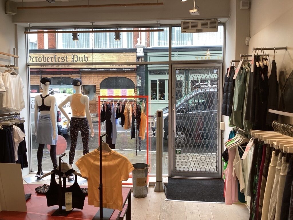 The interior store floor of a Sweaty Betty; a womenswear retailer. Mannequins modelling clothes are displayed from the front window.