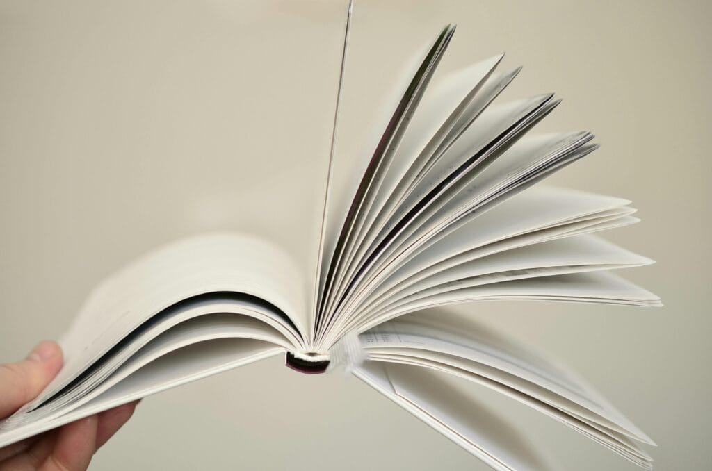 A photograph of an open book being flung open with various pages opened and flapping.