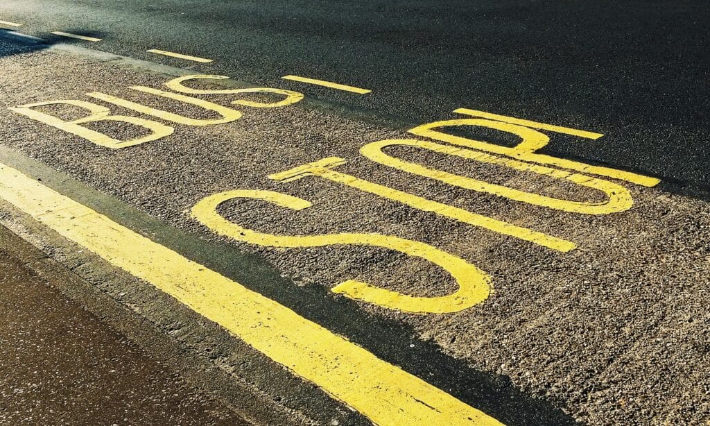 A close up photo of yellow text "Bus stop" painted onto a road.