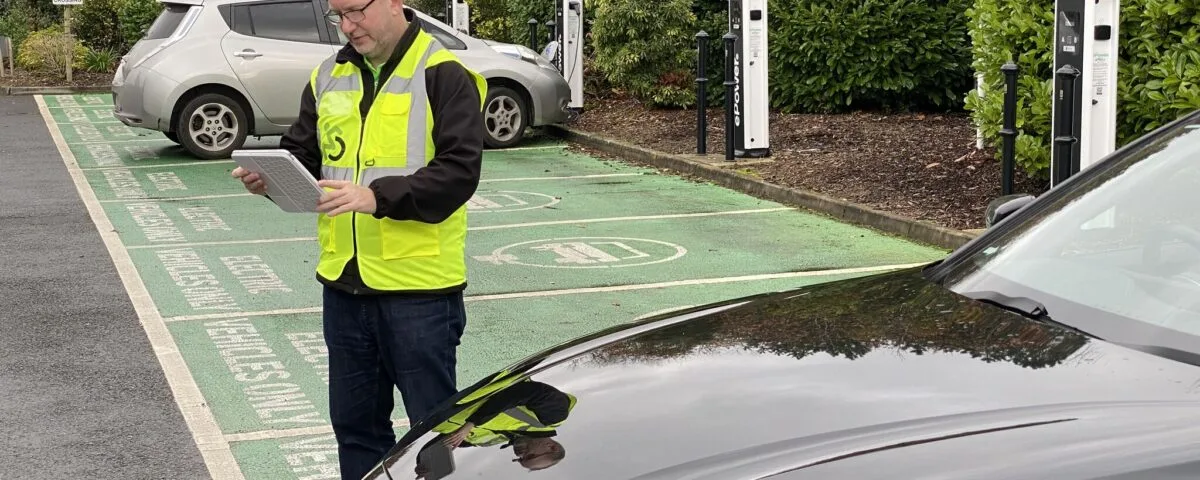 481177445_1039676131490342_445828475820185622_n Direct Access’ Steve Dering in high vis jacket with tablet. Two electric cars are parked in a ten bay charging station.