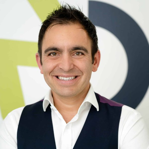 A portrait photograph of Steven Mifsud MBE smiling with the Direct Access wheelchair logo in the background.