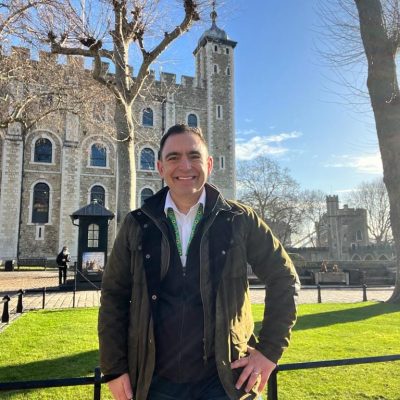 A photo of Steven Mifsud poses for a photo on a sunny day with the White Tower in London in the background