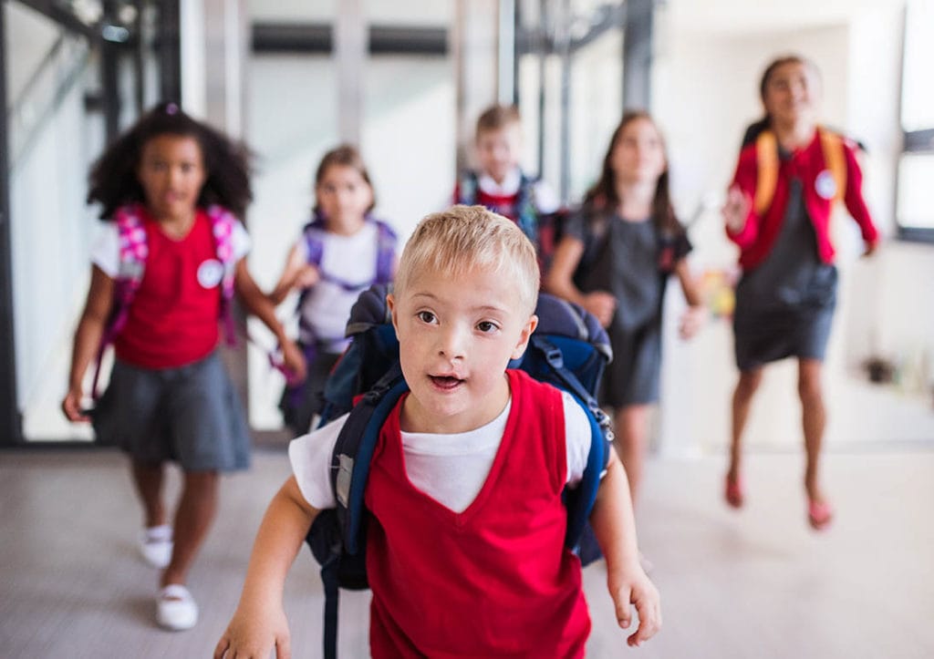 A down-syndrome school boy running with group of children in corridor