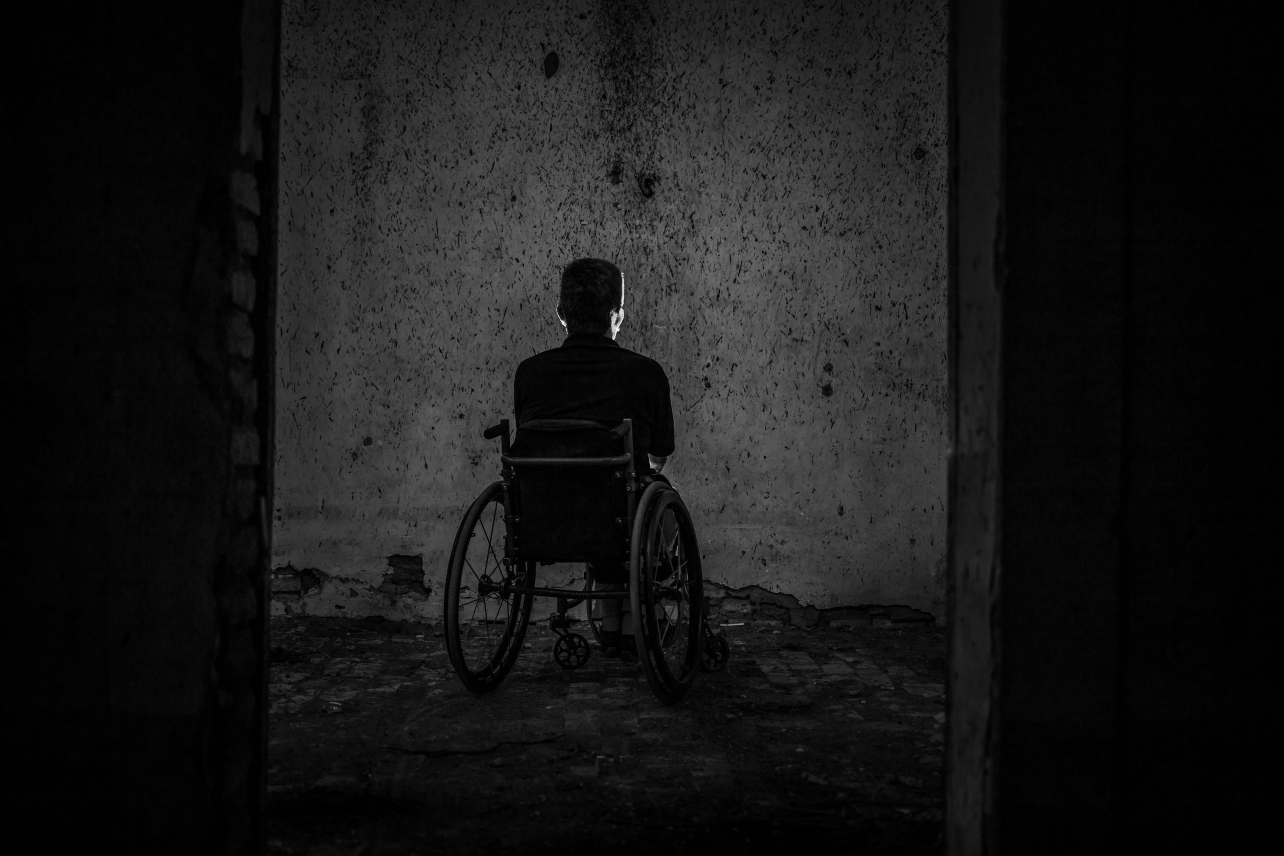 Person in a wheelchair in a dark room.