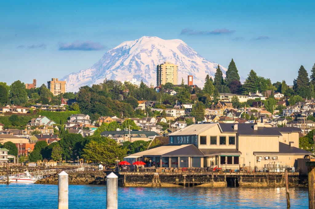 A landscape photograph of Tacoma Washington across a river with Mt. Rainier in the distance during the afternoon.