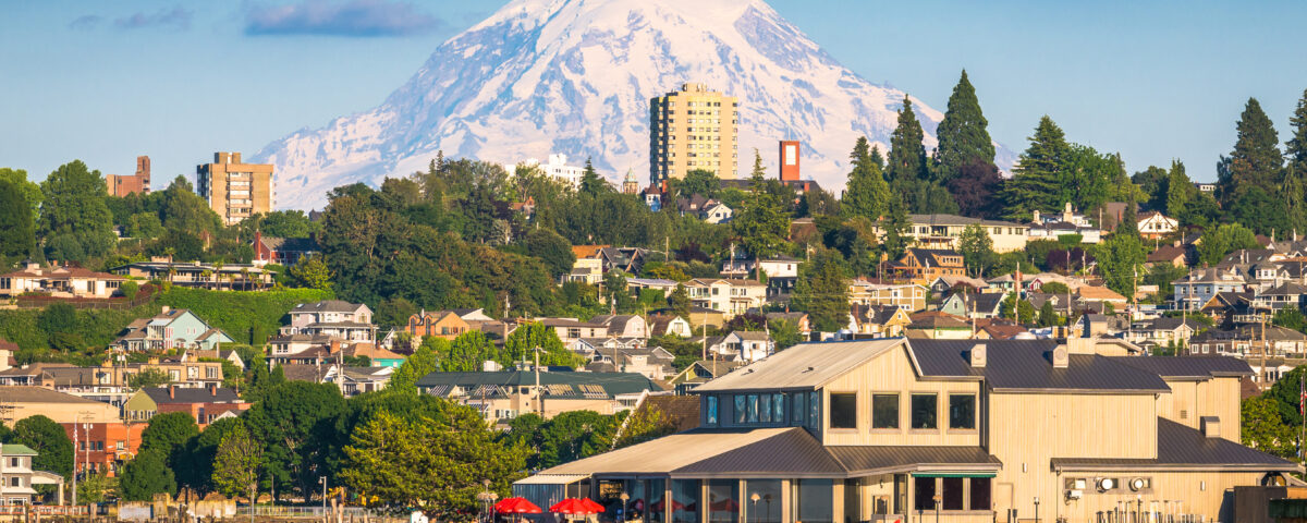A landscape photograph of Tacoma Washington across a river with Mt. Rainier in the distance during the afternoon.