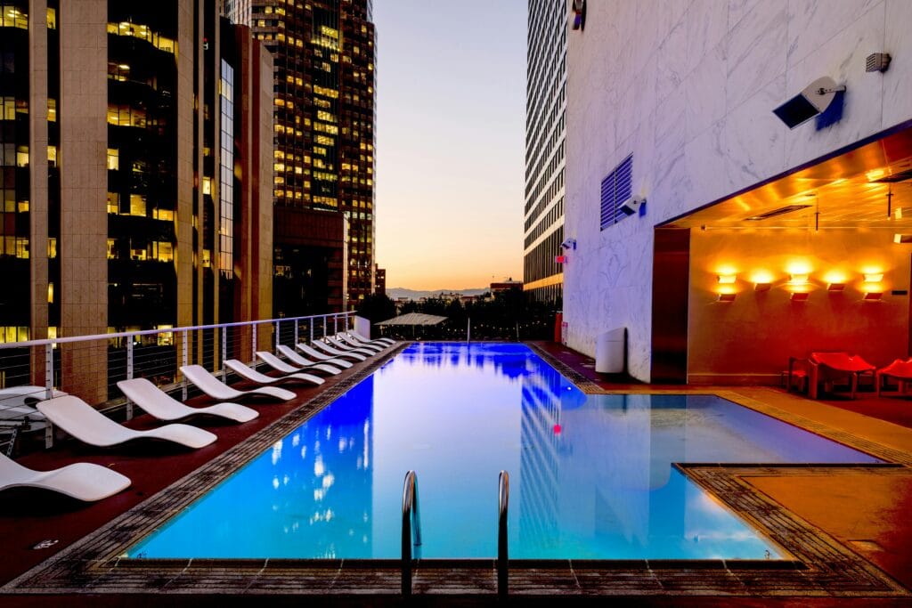 A photograph of a luxury apartment poolside area in a city featuring outdoor deck chair seating.