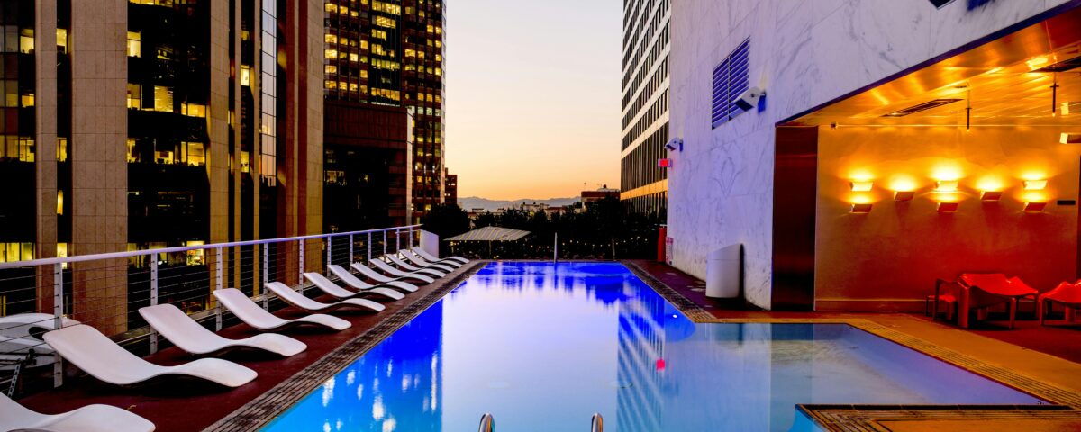 A photograph of a luxury apartment poolside area in a city featuring outdoor deck chair seating.