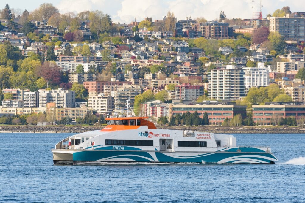 A wide shot photograph of a Kitsap Transit fast ferry going along a river.