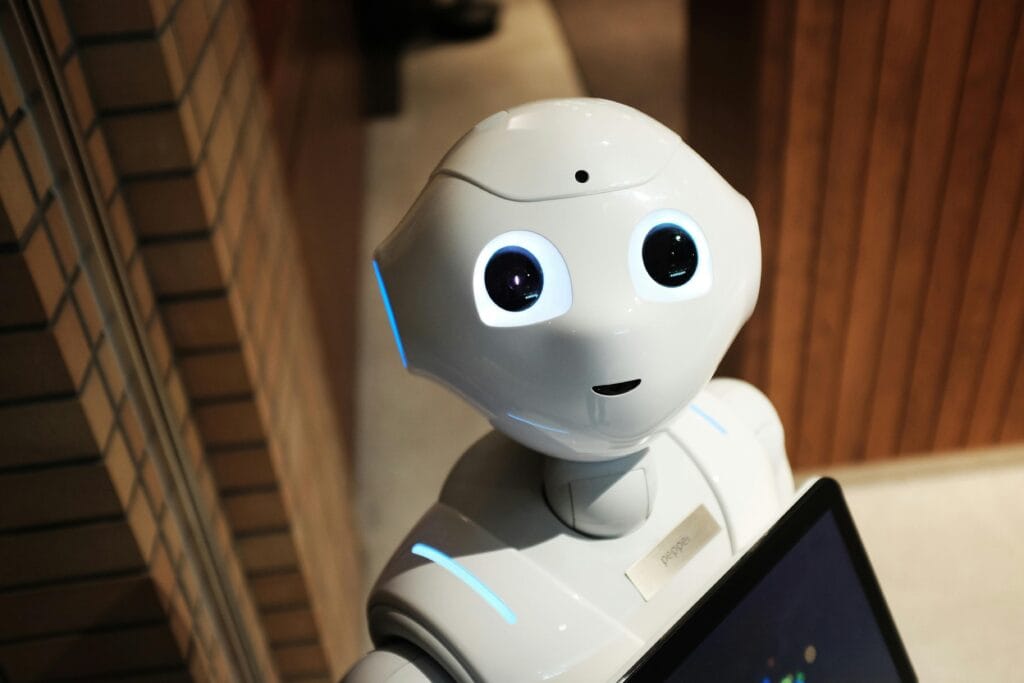 A white robot in a living room setting looking up at the camera and smiling.