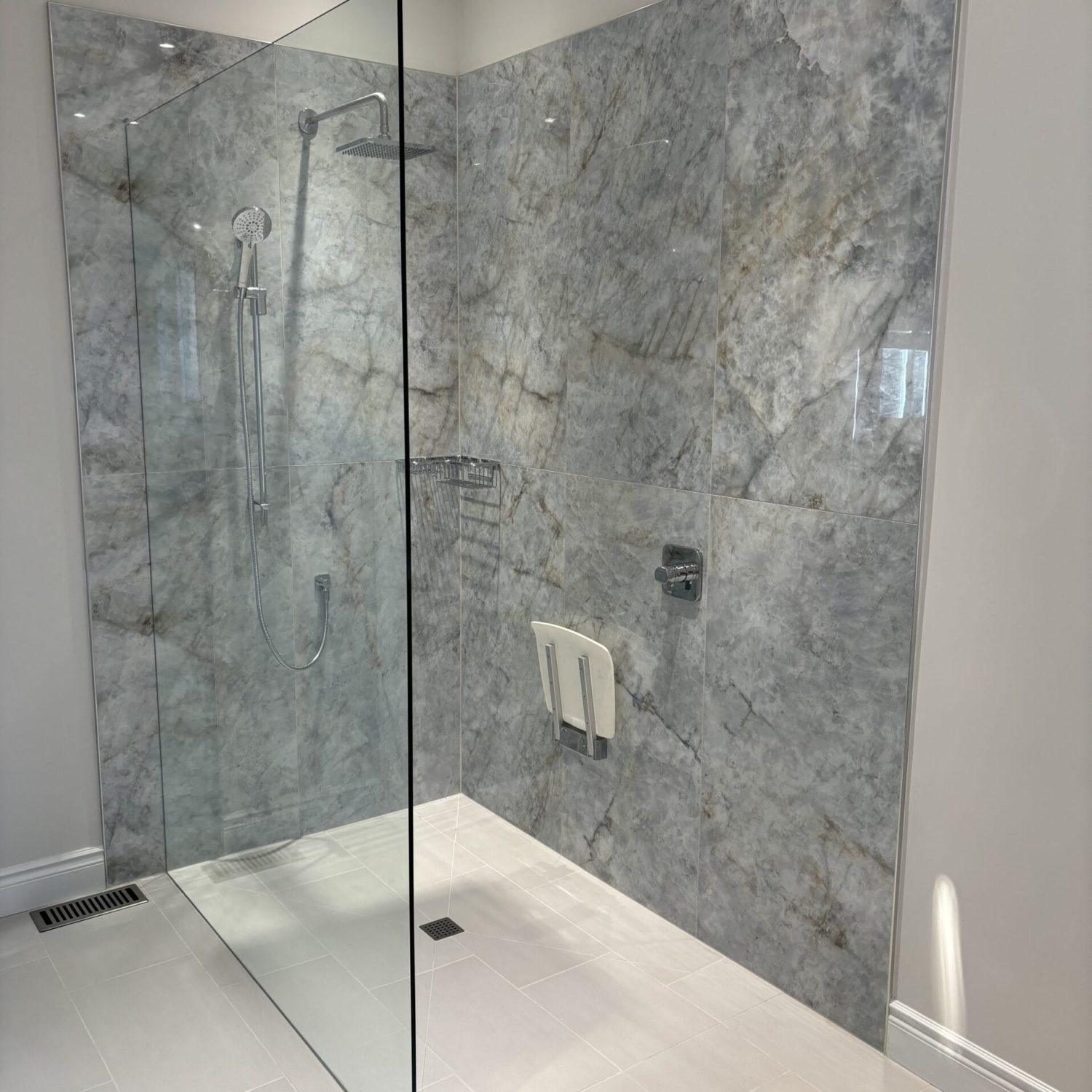 A photo of a modern curbless shower with marble tiling.